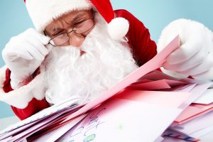 Image of Santa Claus in front of heap of letters reading one of them