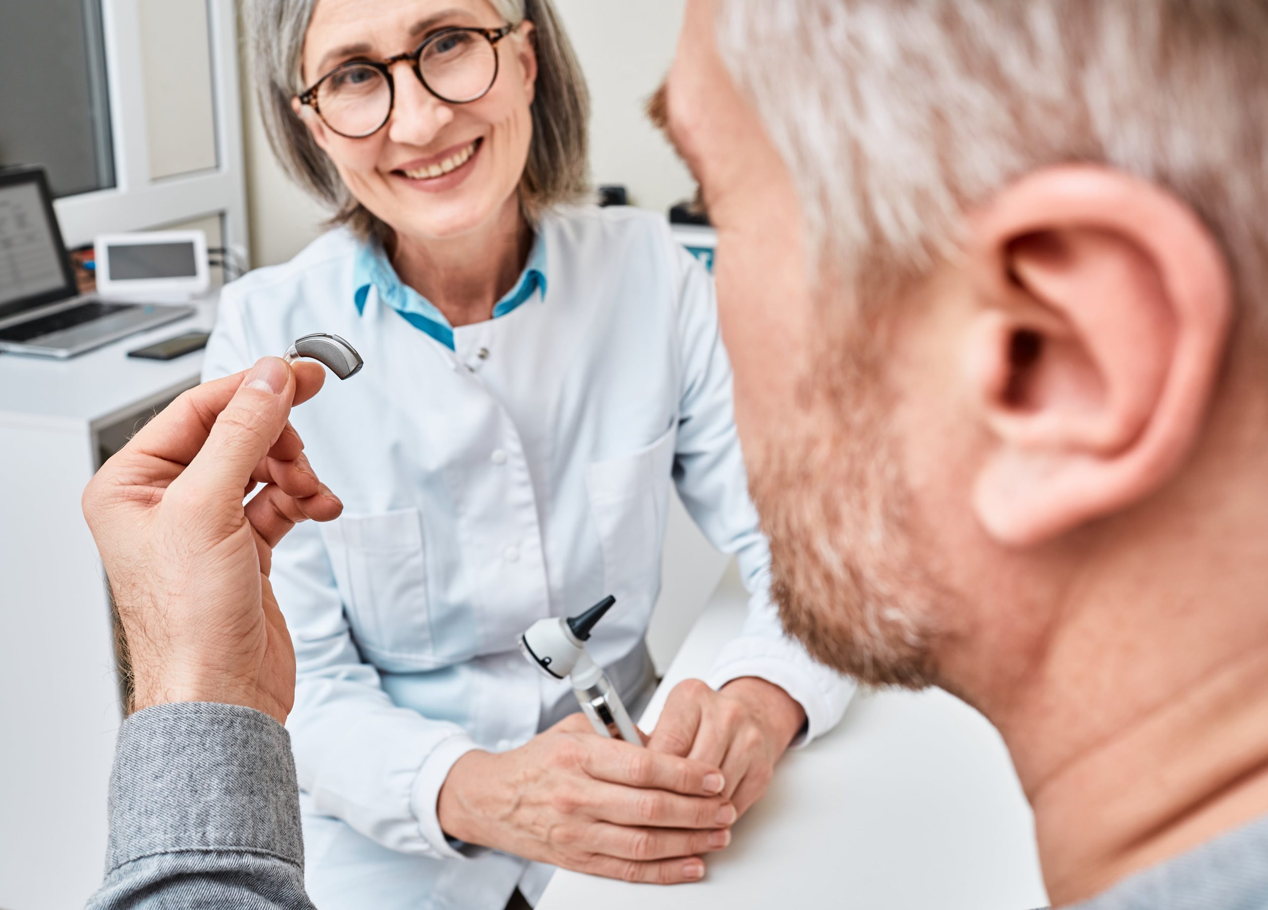 audiologist helping patient with hearing aid